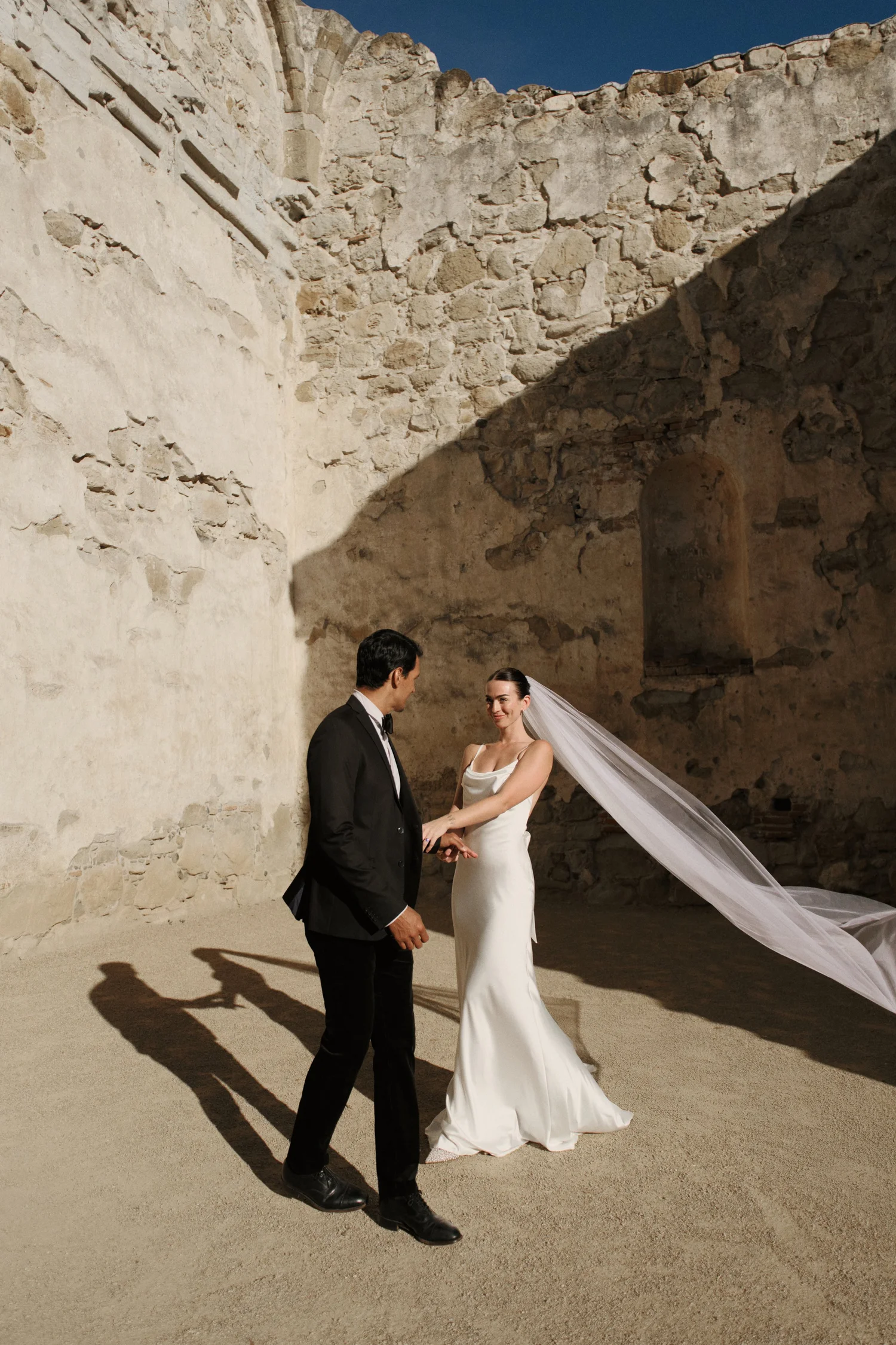 Wedding couple in sunlit stone architecture